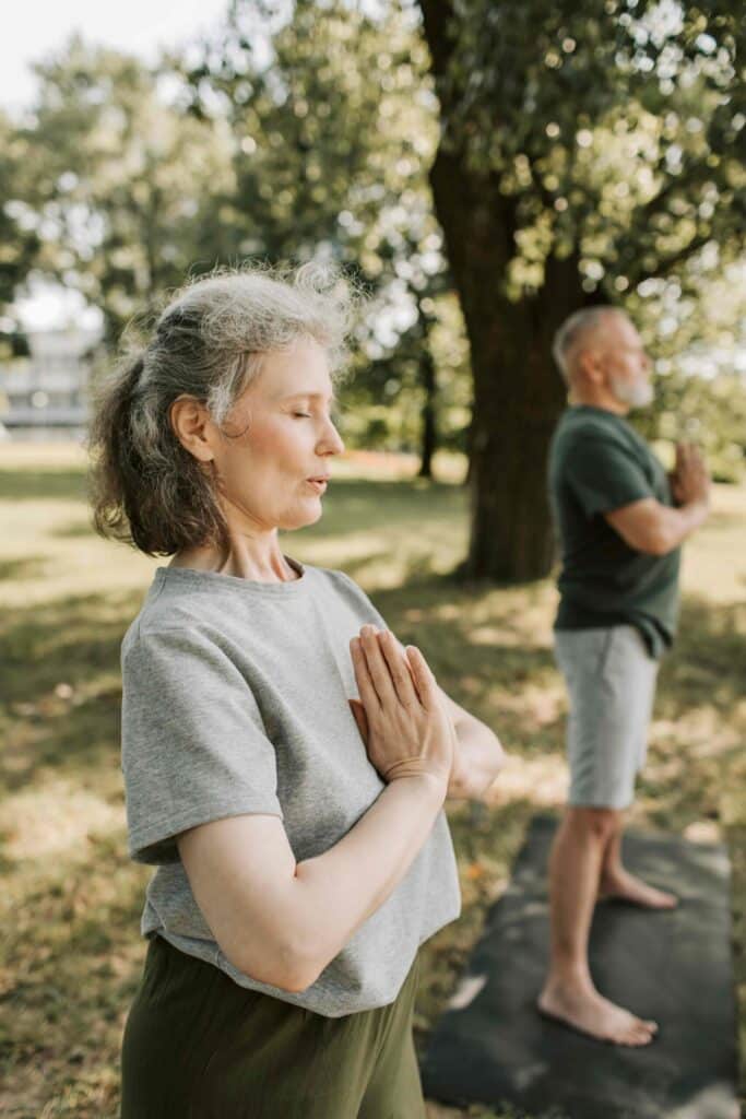 older couple outside doing yoga and breathing exercises